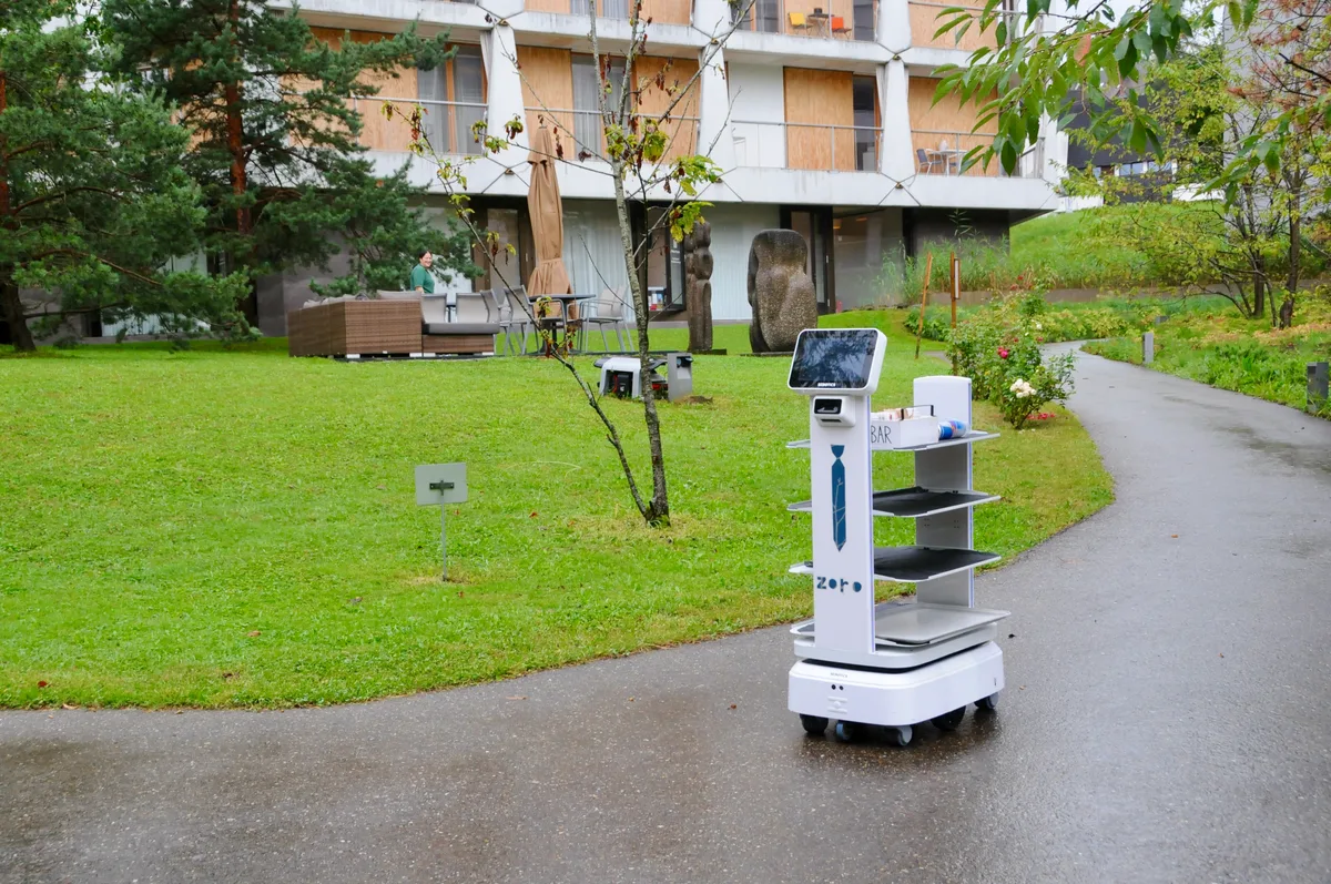 Man sieht einen Serviceroboter durch den Park der Zollinger Stiftung fahren.